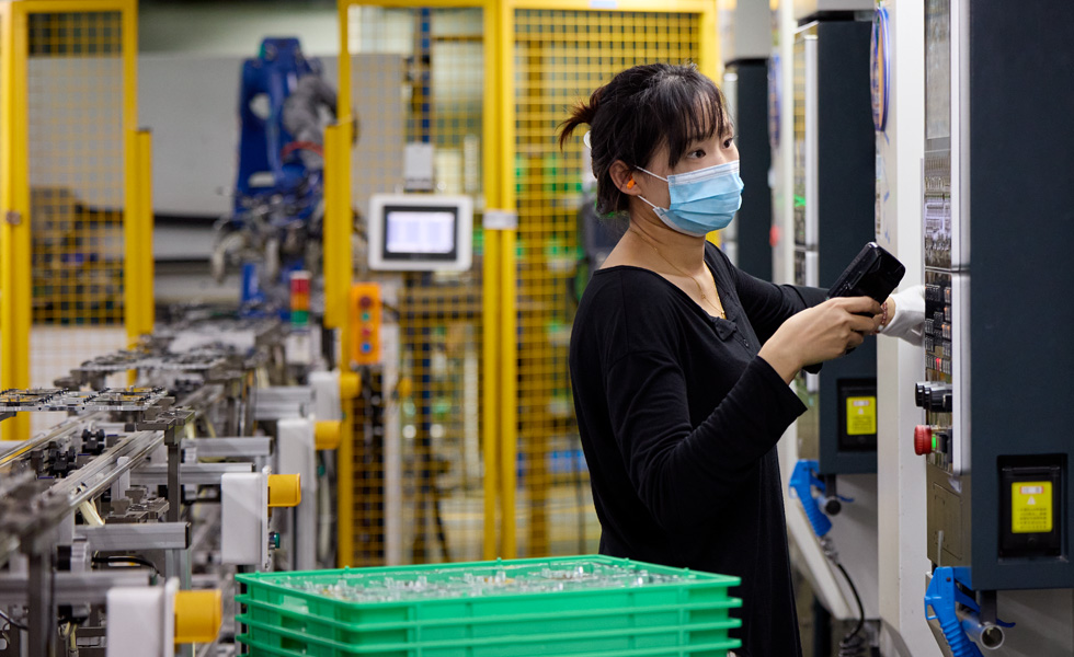 An employee in a component manufacturing facility operates a machine